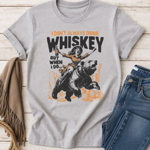 Load image into Gallery viewer, Gray t-shirt with graphic design featuring a woman riding a bear and text, displayed with jeans and a blanket on a wooden surface.

