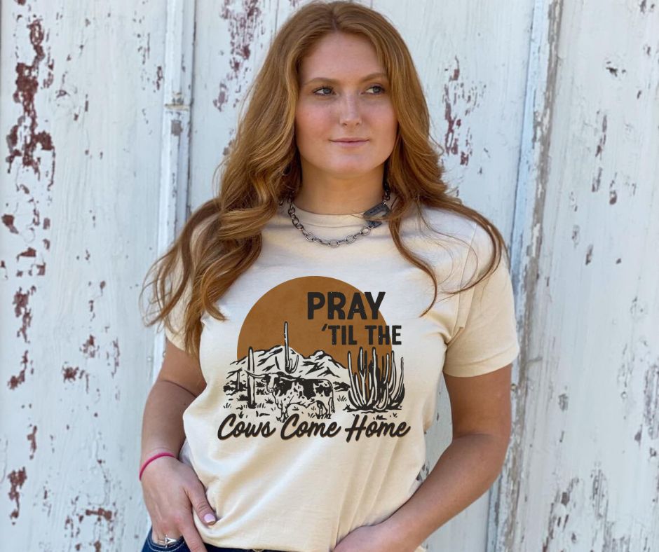 Woman wearing a beige t-shirt with a graphic and text against a rustic wooden background
