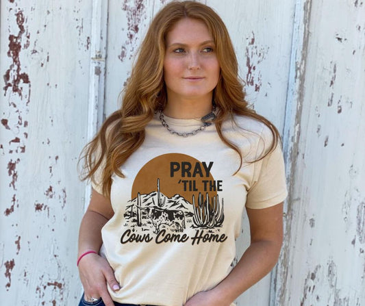 Woman wearing a beige t-shirt with a graphic and text against a rustic wooden background