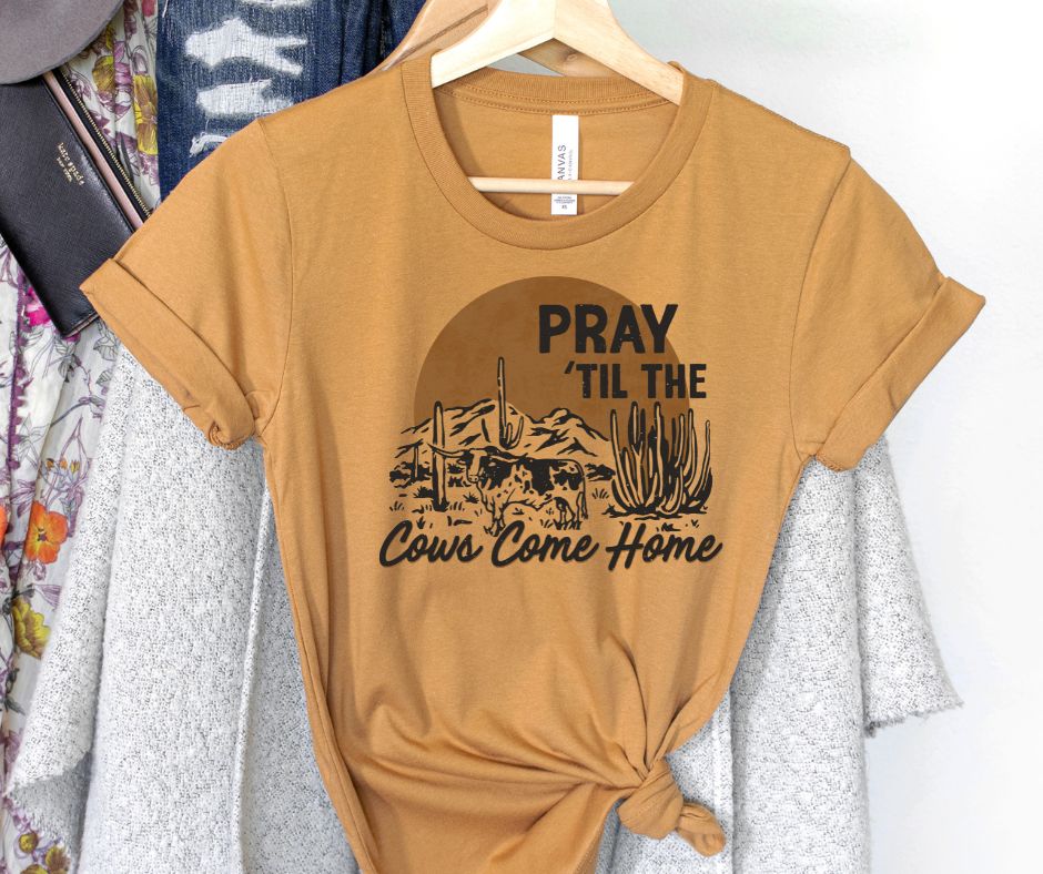Mustard yellow t-shirt with graphic design and text on a hanger against a white background