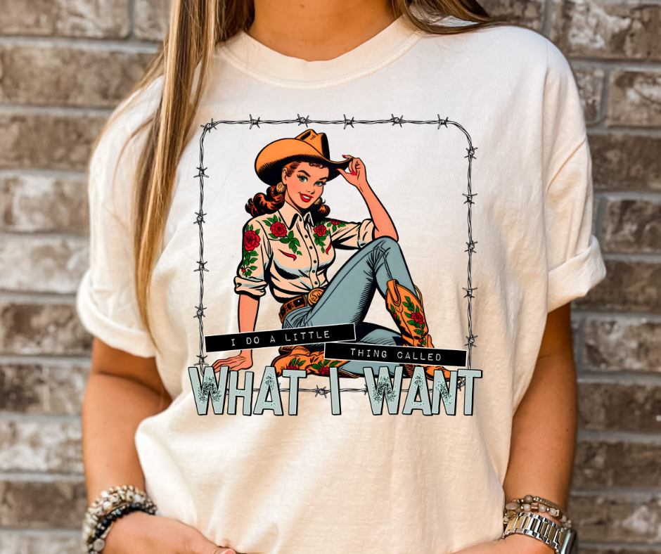 Person wearing a white t-shirt with a graphic design of a woman in a cowboy hat and boots, surrounded by barbed wire, with text 'What I Want'.